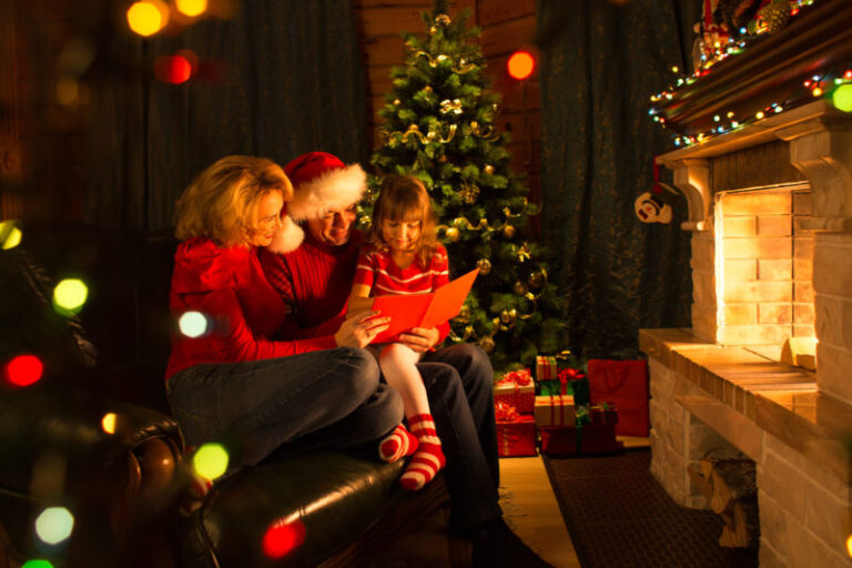 mom and dad reading daughter a book in front of fireplace